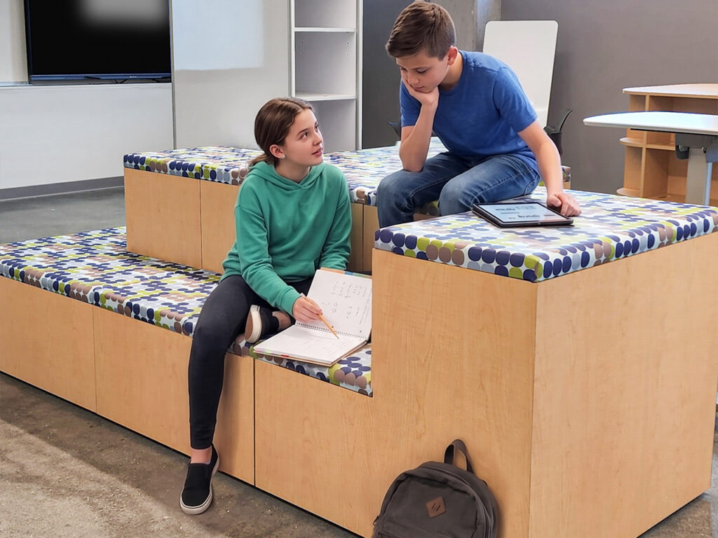 Students engaged in informal learning using tiered FLEX Steps EVO seating in a media center lounge.